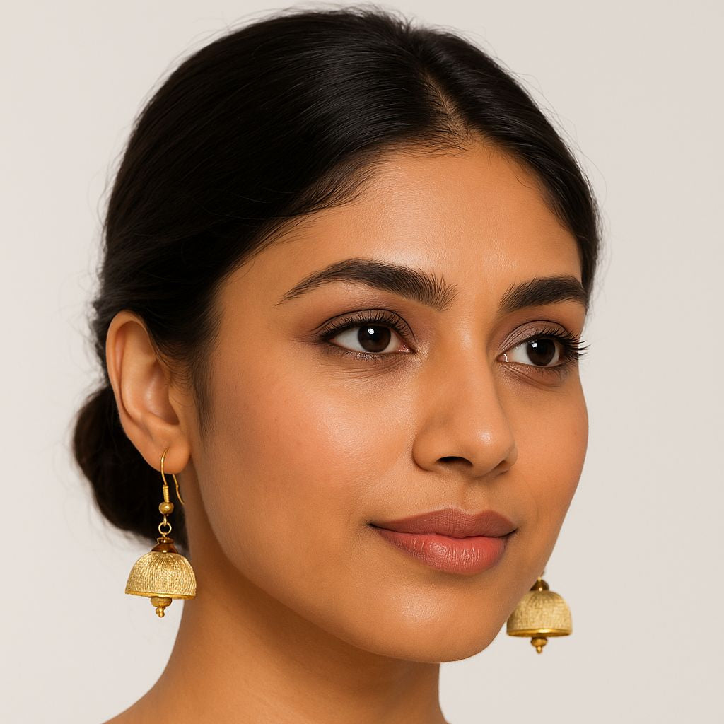 Woman wearing gold earrings against a plain background