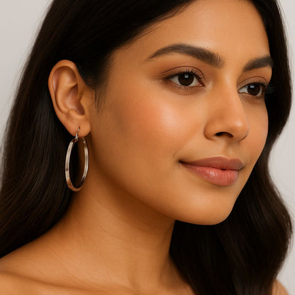 Close-up of a woman wearing hoop earrings with a neutral background